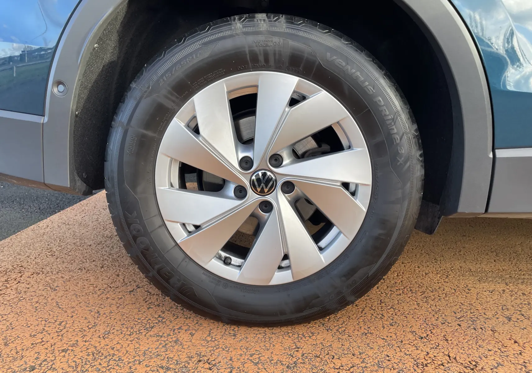 Gros plan sur la roue avant gauche du Volkswagen Tiguan 2024 bleu Nightshade avec jante alliage argentée.