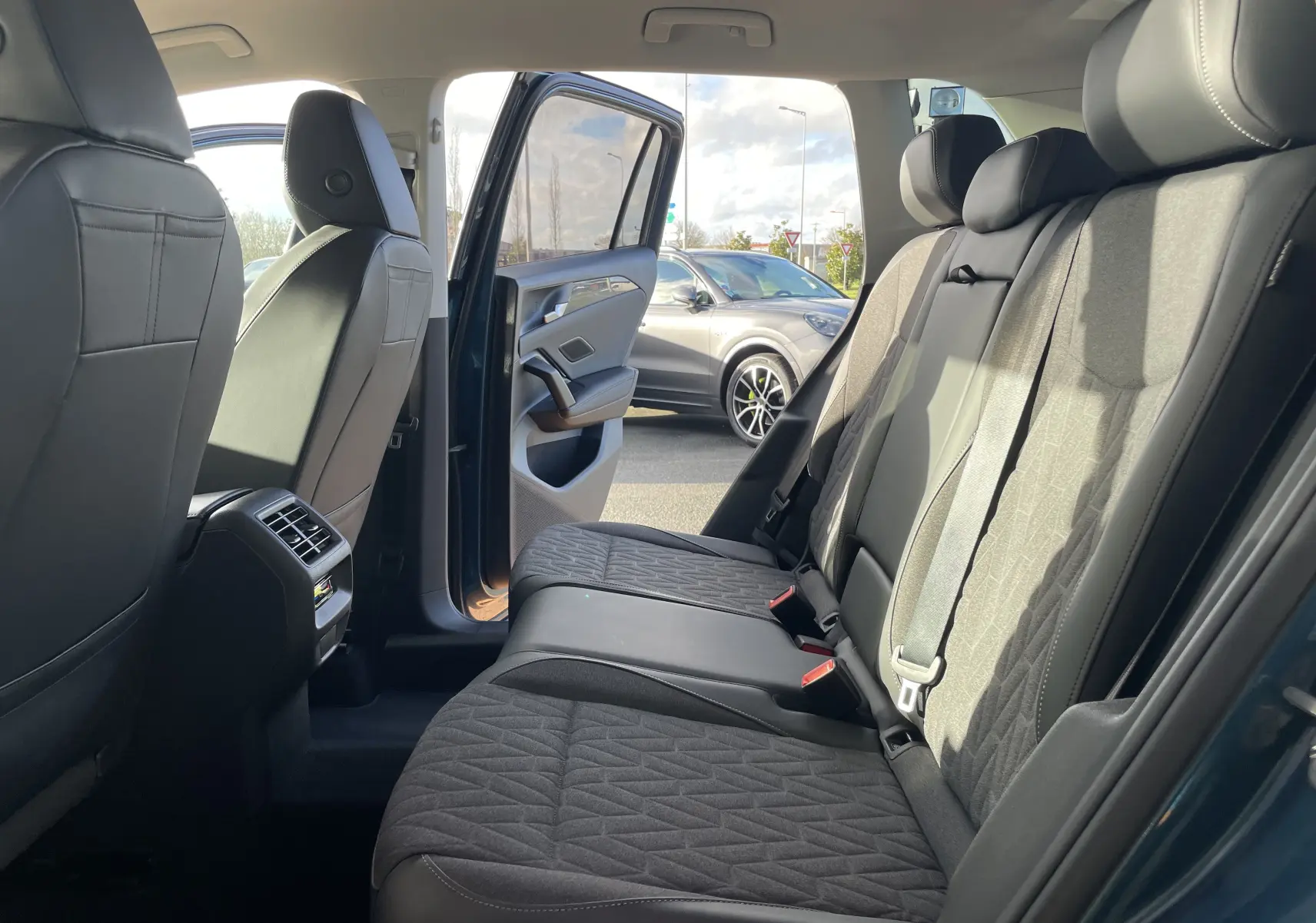 Vue intérieure côté droit sur la banquette arrière du Volkswagen Tiguan 2024 bleu Nightshade avec portes ouvertes.