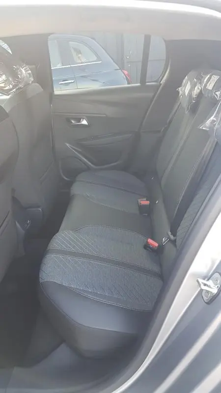 Vue intérieure côté droit des sièges arrière gris de la Peugeot 208 Hybrid 110 e-DCS6 Allure 2025 avec habillage tissu et cuir.