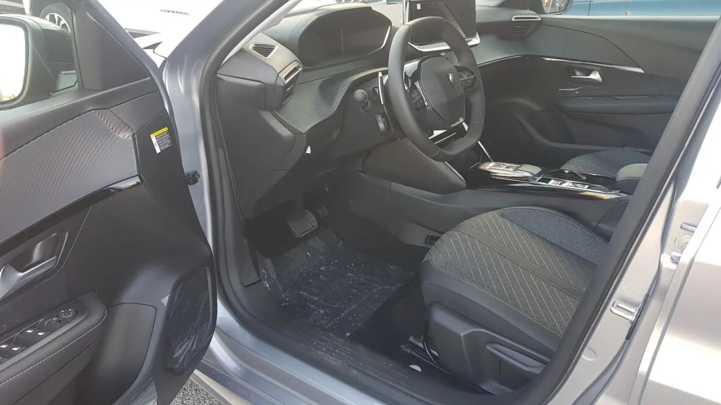 Intérieur côté conducteur de la Peugeot 208 Hybrid gris 2025, avec volant compact et tableau de bord moderne.