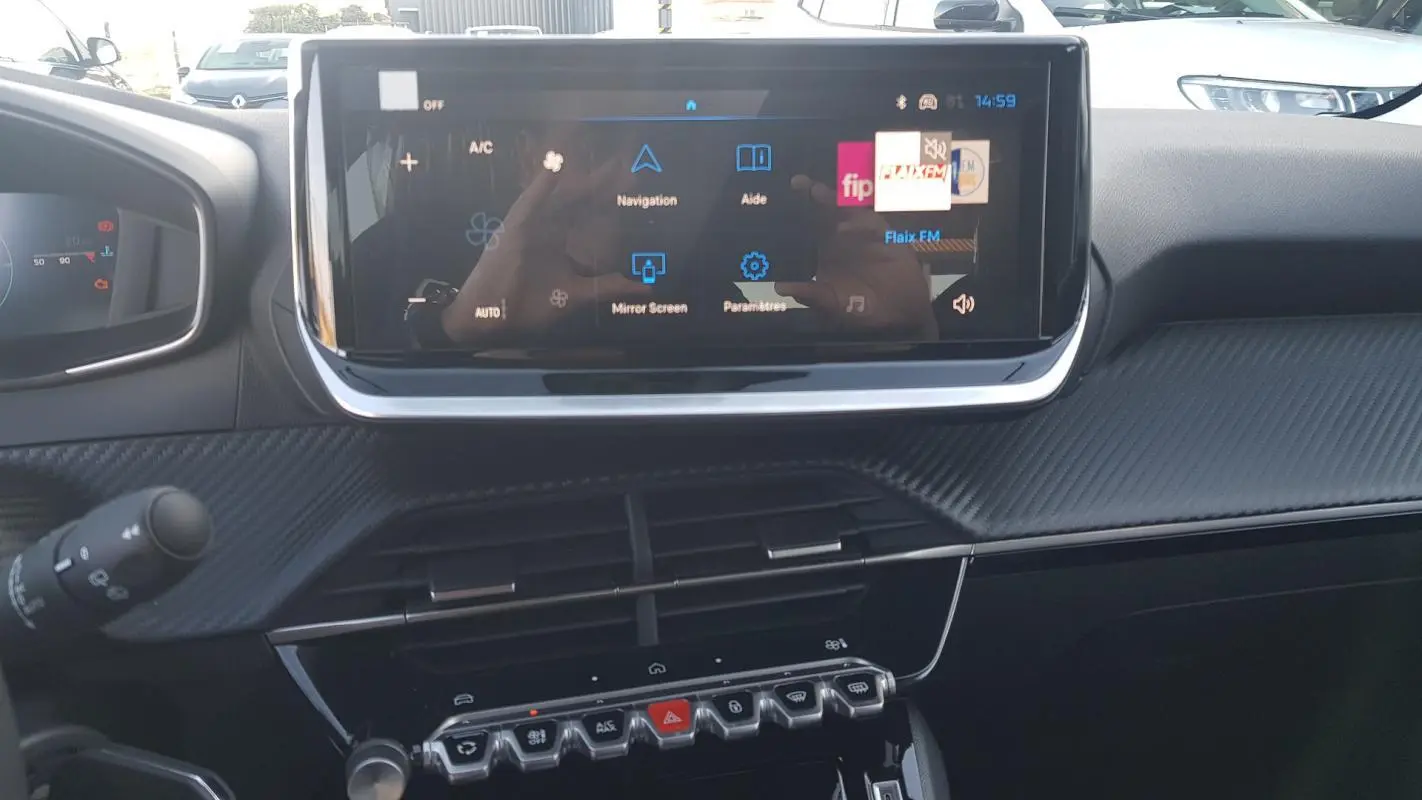 Vue rapprochée de l’écran tactile central et du tableau de bord noir de la Peugeot 208 Hybrid 110 gris, année 2025.