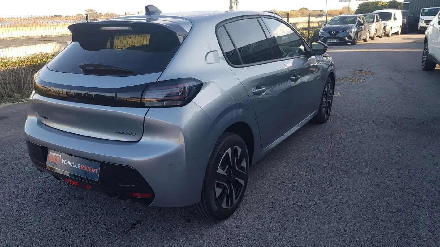 Vue 3/4 arrière droite d'une Peugeot 208 Hybrid 110 gris métallisé avec jantes alliage et antenne requin.