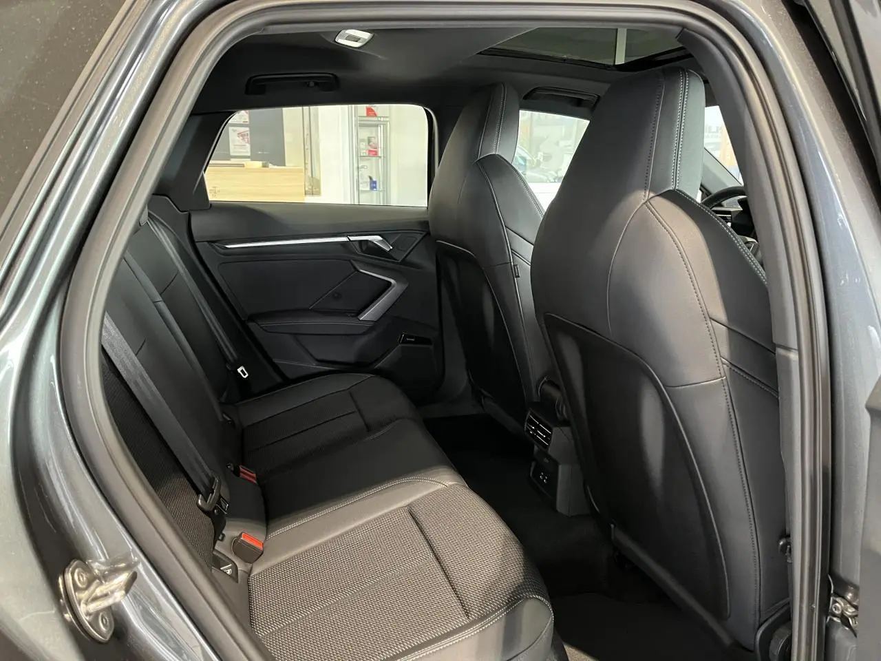 Vue intérieure côté droit de l’Audi A3 Sportback 2025 gris, montrant les sièges arrière en cuir noir et les ports USB arrière.