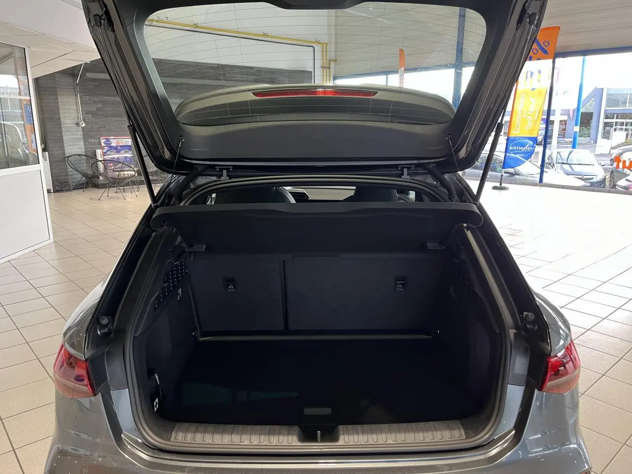 Coffre ouvert d'une Audi A3 Sportback gris, vue arrière intérieure montrant l'espace de chargement vide.