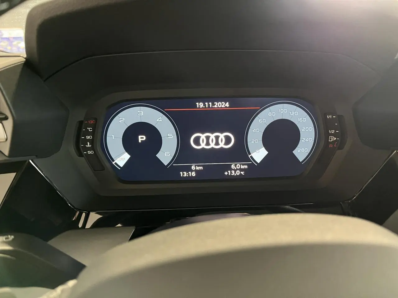 Vue rapprochée du tableau de bord numérique de l'Audi A3 Sportback gris, affichant les compteurs et logo Audi central.