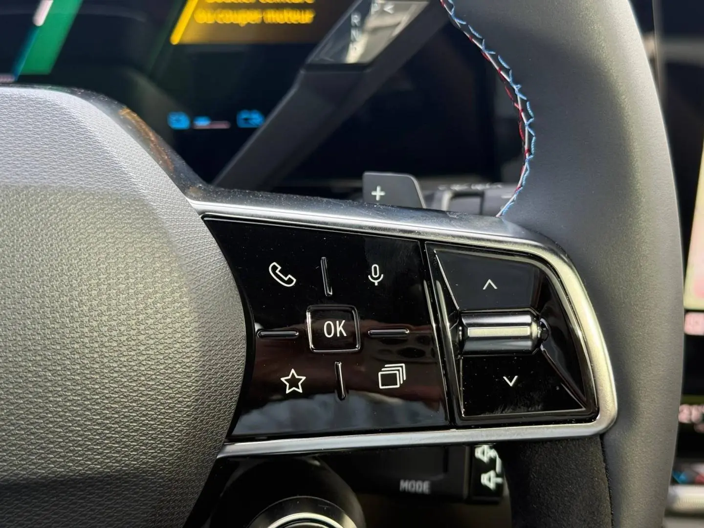 Gros plan sur les commandes multifonctions côté gauche du volant du Renault Austral gris Schiste satin avec surpiqûres tricolores.