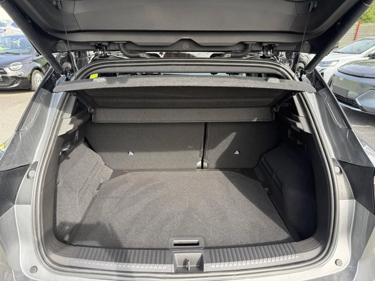 Coffre ouvert vue arrière du Renault Austral gris Schiste satin avec intérieur noir et cache-bagages déployé.