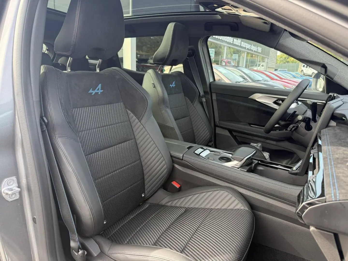 Vue intérieure côté conducteur du Renault Austral gris avec sièges sport en cuir et Alcantara esprit Alpine brodés bleu.