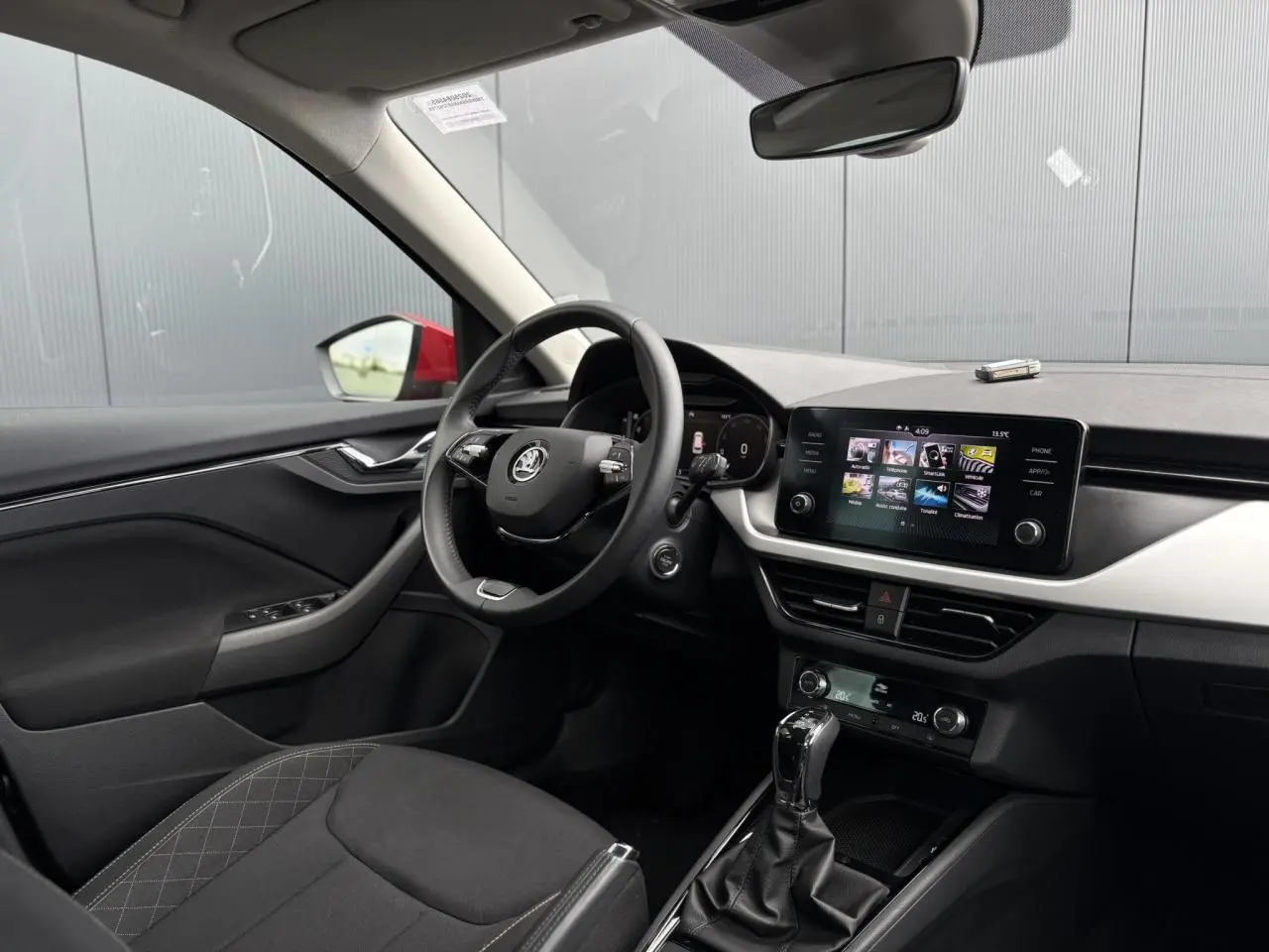 Intérieur du Skoda Kamiq TSI 110 DSG Ambition 2024, vue côté conducteur, volant cuir et écran tactile central visible.