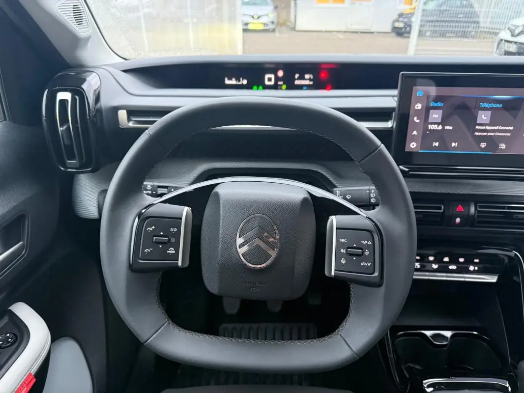 Vue intérieure centrée sur le volant de la Citroën C3 2025, avec tableau de bord numérique et écran tactile.