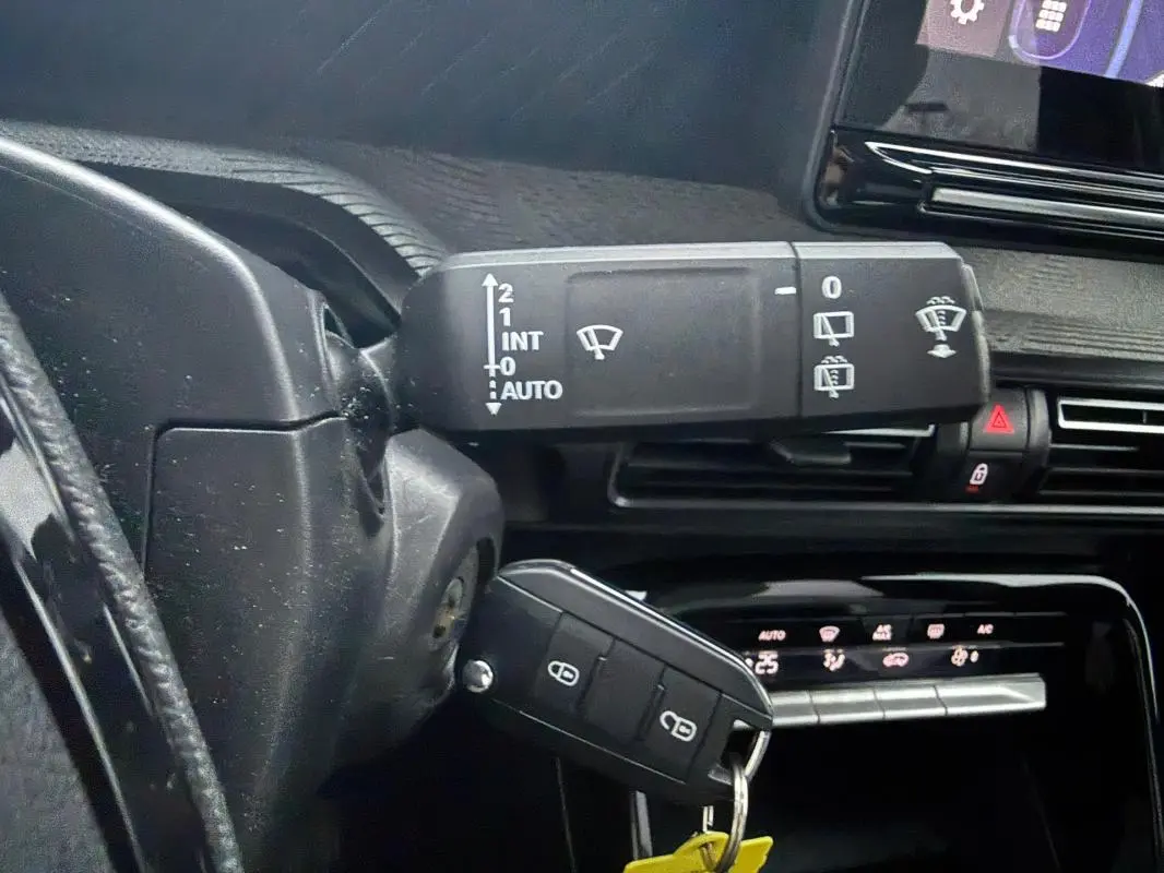 Gros plan sur la commande des essuie-glaces et la clé dans le contact d’une Citroën C3 gris, tableau de bord en arrière-plan.