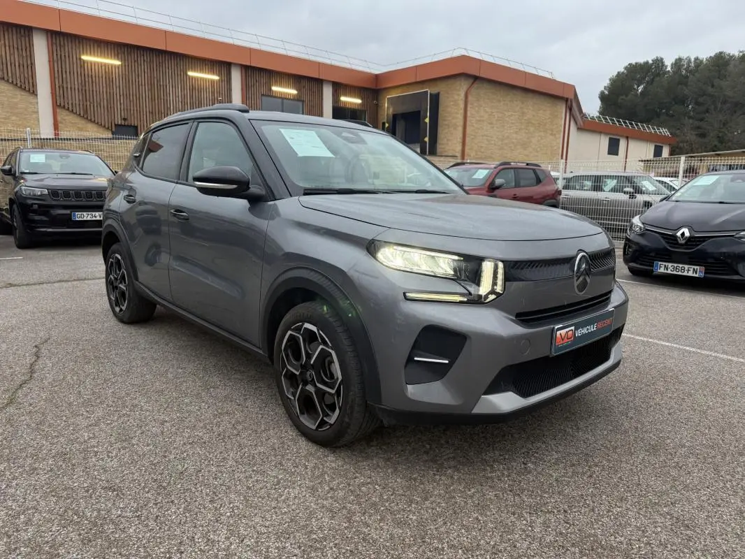 Vue 3/4 avant gauche d'une Citroën C3 Turbo 100 ch gris avec jantes alliage 17 pouces et barres de toit visibles.