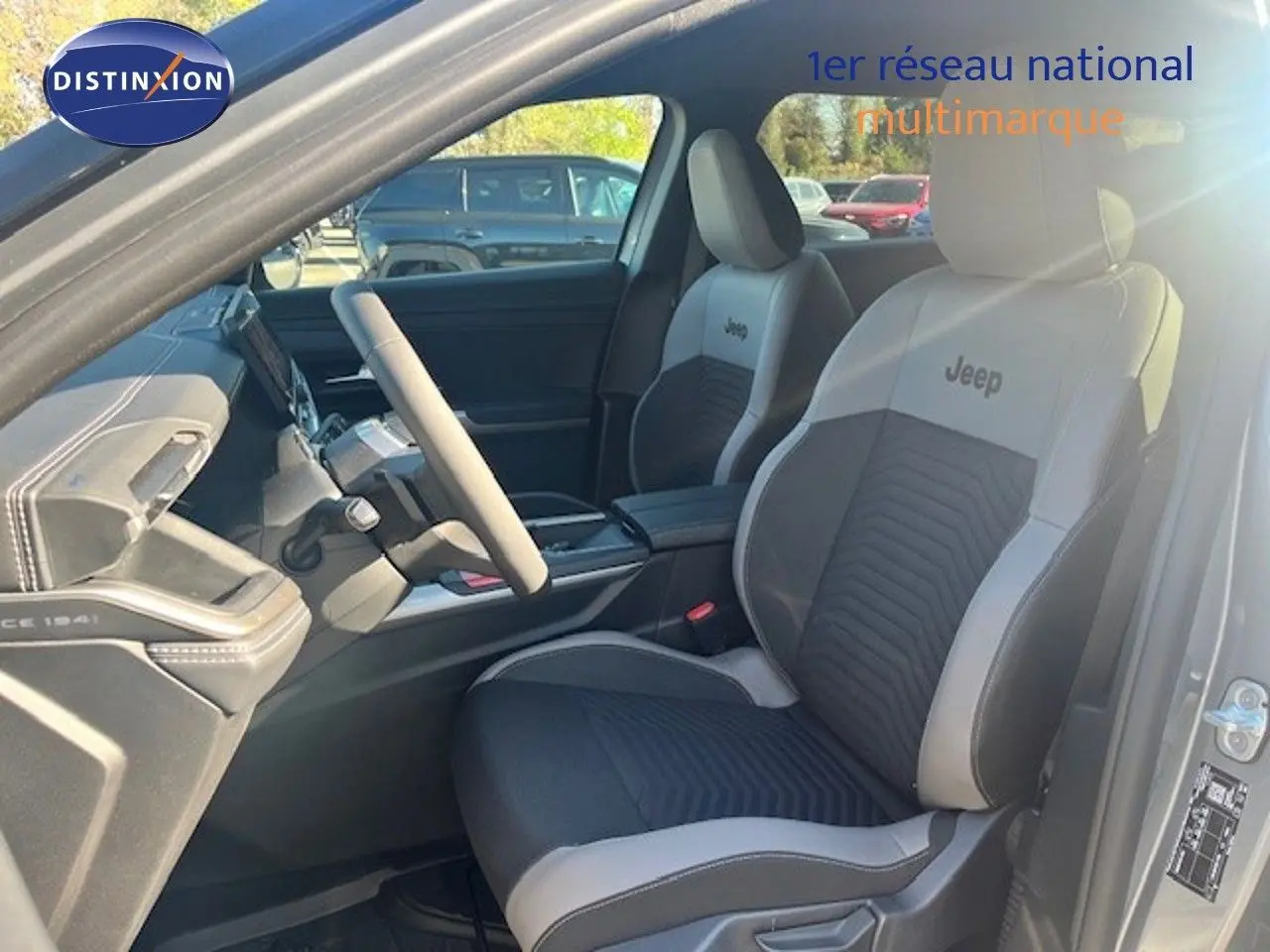 Vue intérieure côté conducteur du Jeep Compass 2026, sièges bi-ton gris et noir avec logo Jeep brodé.