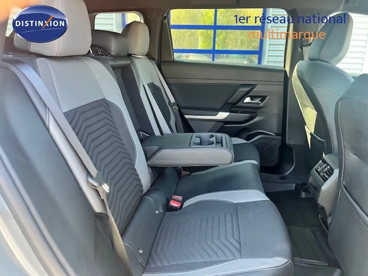 Vue intérieure arrière du Jeep Compass 2026, sièges bicolores gris et noir avec accoudoir central déployé.