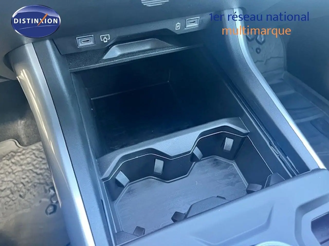 Gros plan sur le rangement central et porte-gobelets noir à l’intérieur du Jeep Compass 2026 gris Yosemite métal avec toit noir.
