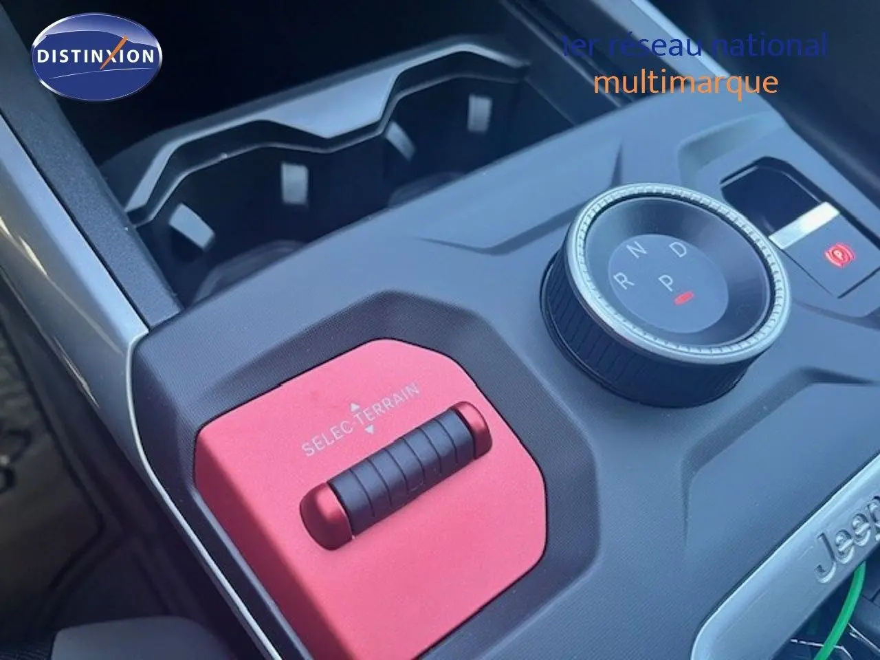 Gros plan sur la console centrale du Jeep Compass 2026 avec molette de boîte auto et sélecteur de terrain rouge.
