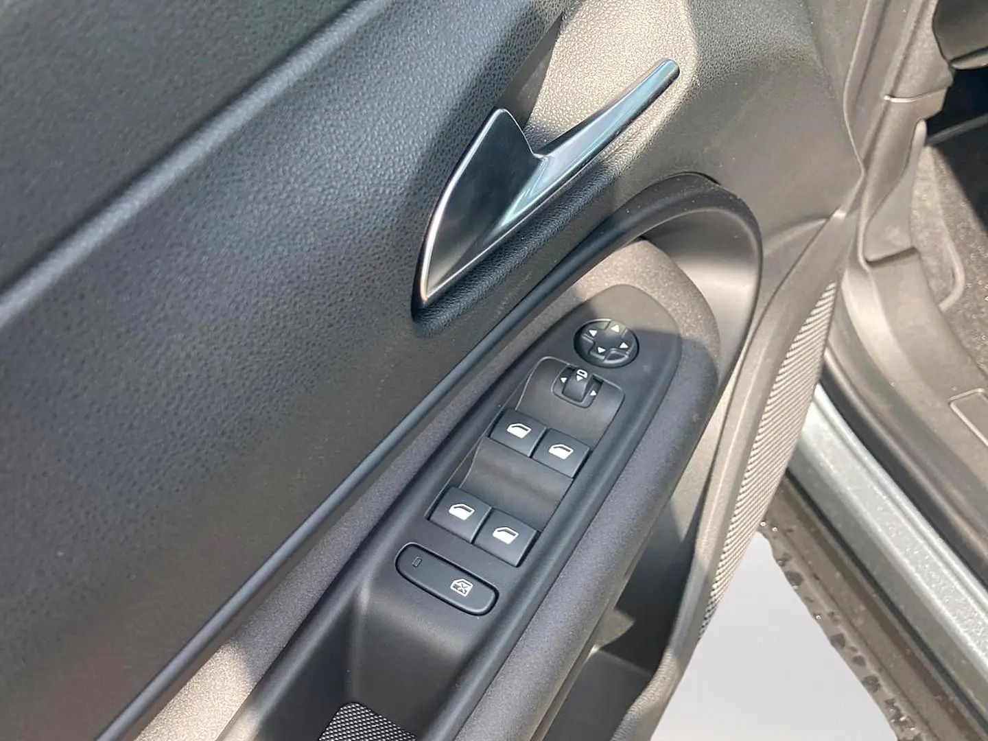 Gros plan sur la porte avant gauche grise de l'Alfa Romeo Junior 1.2 hybride, montrant les commandes des vitres et le bouton de verrouillage.