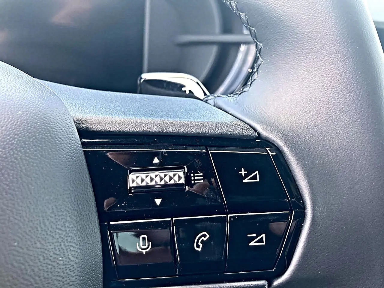 Gros plan sur les commandes noires au volant de l'Alfa Romeo Junior gris, mettant en valeur les boutons de volume et de téléphone.