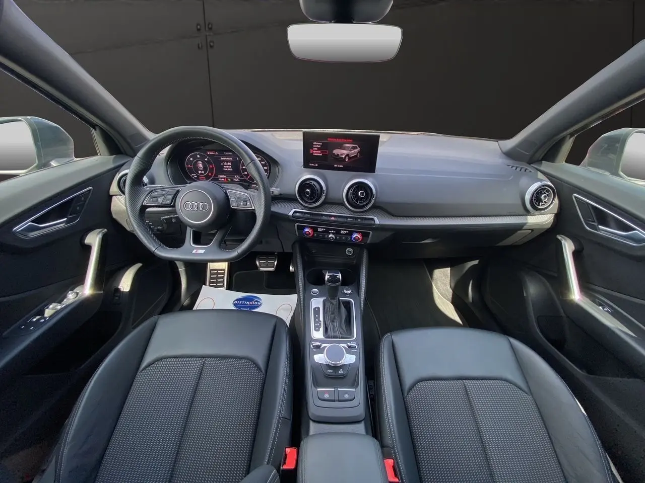 Vue intérieure de l'Audi Q2 35 TDI S-Line 2024, montrant le tableau de bord et les sièges en cuir noir.