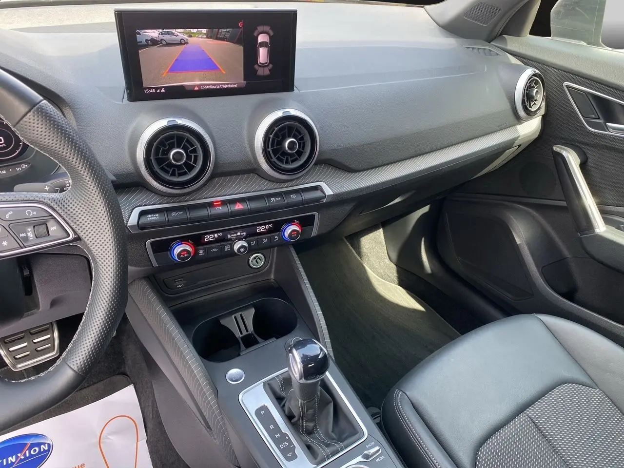 Vue intérieure de l'Audi Q2 35 TDI S-Line montrant le tableau de bord, la caméra de recul à l'écran et la console centrale noire.