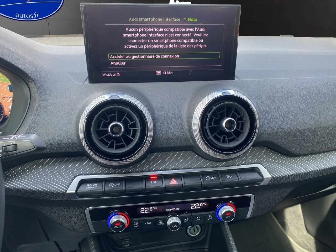 Tableau de bord de l'Audi Q2 35 TDI S-Line 2024 avec écran central et aérateurs ronds en vue frontale rapprochée.