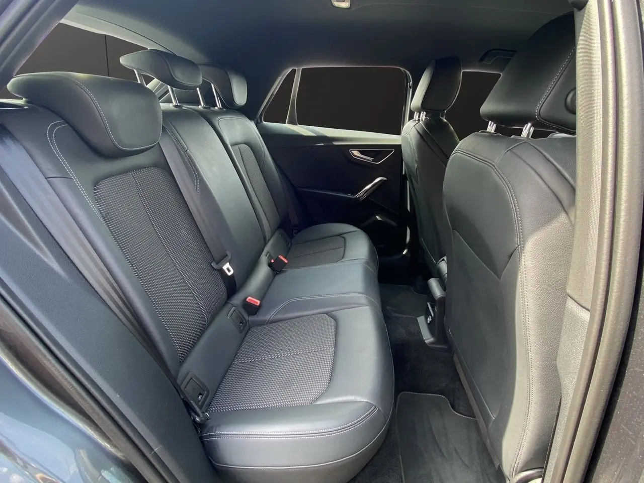 Vue intérieure arrière de l'Audi Q2 35 TDI S-Line avec sièges cuir noir et finitions modernes sur portes.