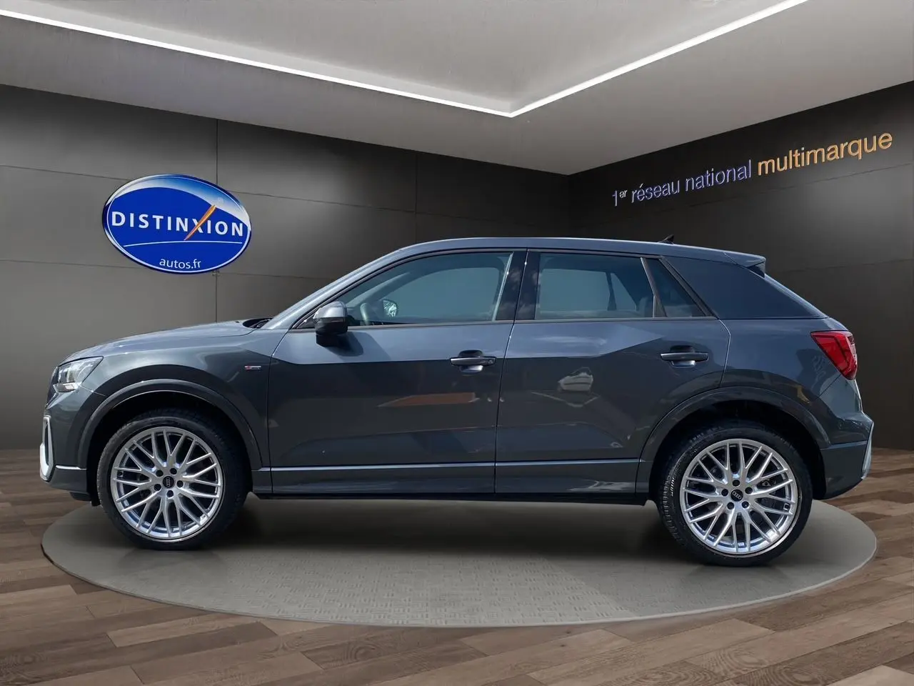 Audi Q2 gris Daytona en profil droit, avec jantes alu Audi Sport 19 pouces et finition S line visible sur l'aile avant.