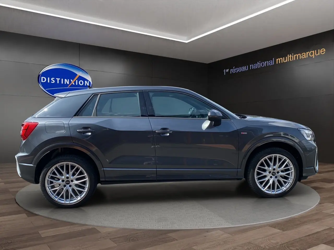 Audi Q2 S line gris Daytona en profil côté gauche, avec jantes aluminium 19 pouces et hayon électrique visible.