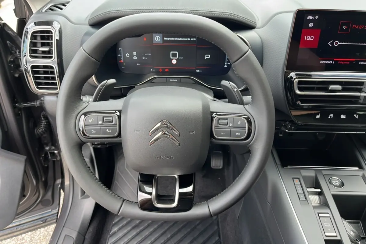 Vue centrée sur le volant et tableau de bord du Citroën C5 Aircross Hybrid 2025 avec écran tactile et commandes intégrées.