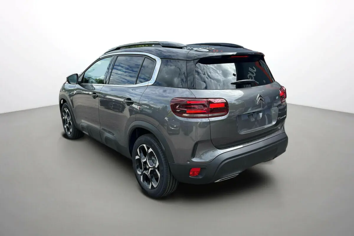 Vue 3/4 arrière droite du Citroën C5 Aircross 2025 gris platinium avec toit noir et jantes distinctives.