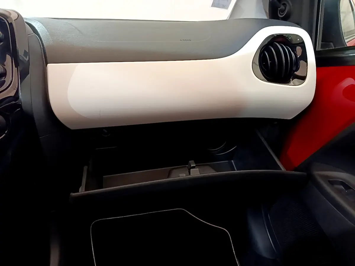 Intérieur côté passager d'une Peugeot 108 rouge, tableau de bord bicolore avec boîte à gants ouverte.