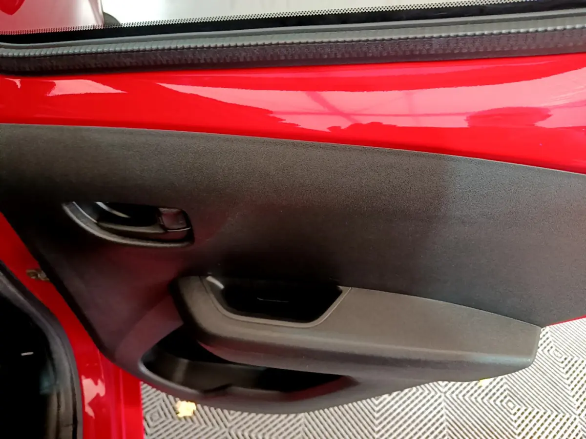 Gros plan sur la porte intérieure noire côté gauche d'une Peugeot 108 rouge 2017 avec poignée intégrée.