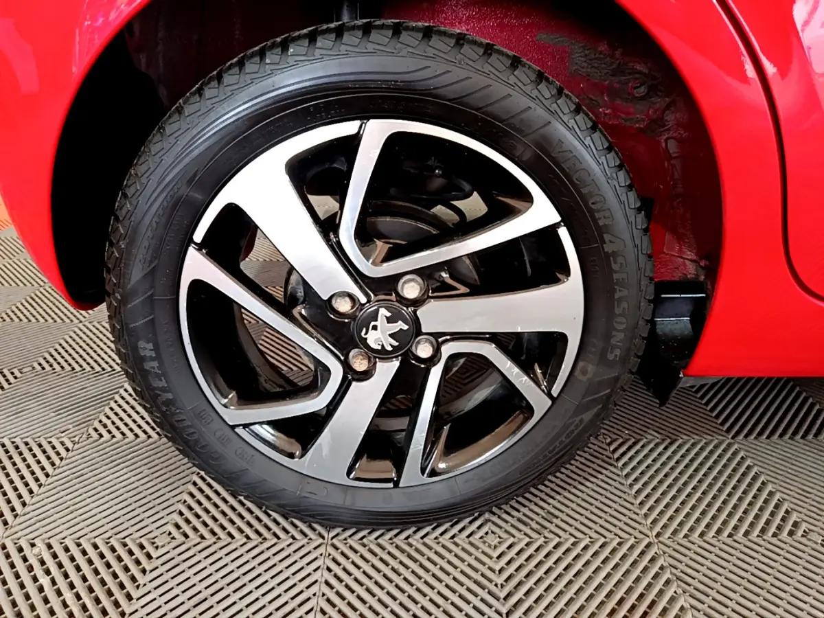 Gros plan sur la roue avant droite du Peugeot 108 rouge, mettant en valeur la jante alliage bicolore et le pneu Goodyear.