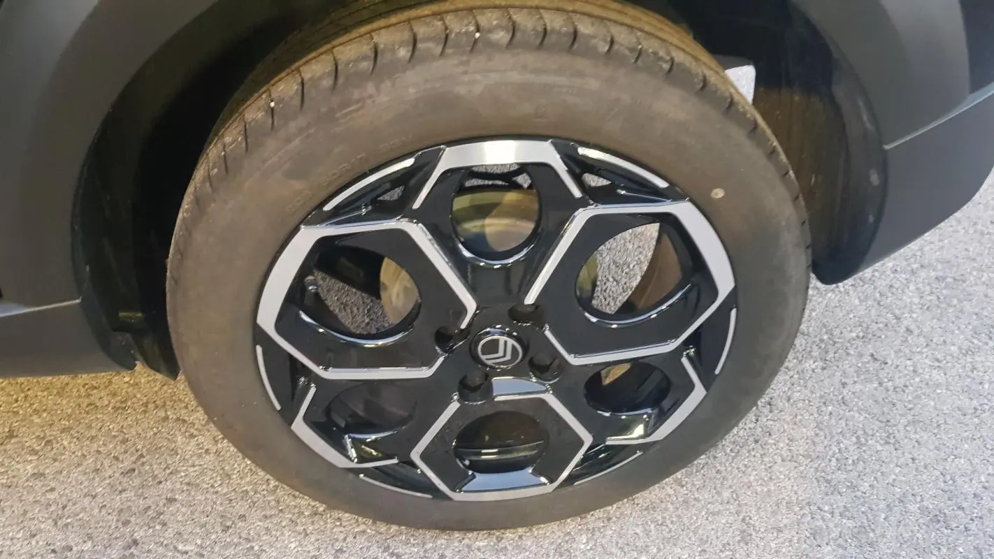 Gros plan sur la jante alliage noire et argentée de la CITROEN C3 Turbo 100 ch BVM6 Max noire, roue avant gauche.