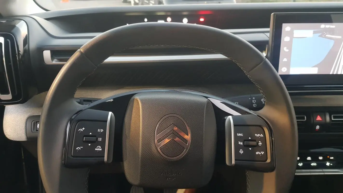 Vue rapprochée du volant noir de la Citroën C3 2025 avec commandes intégrées et tableau de bord numérique.