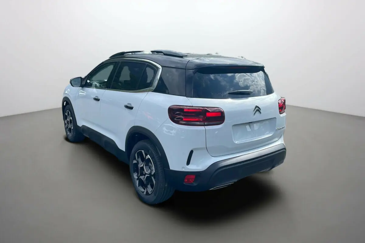 Vue 3/4 arrière gauche du Citroën C5 Aircross hybride 2025 blanc okénite avec toit noir et jantes stylées.