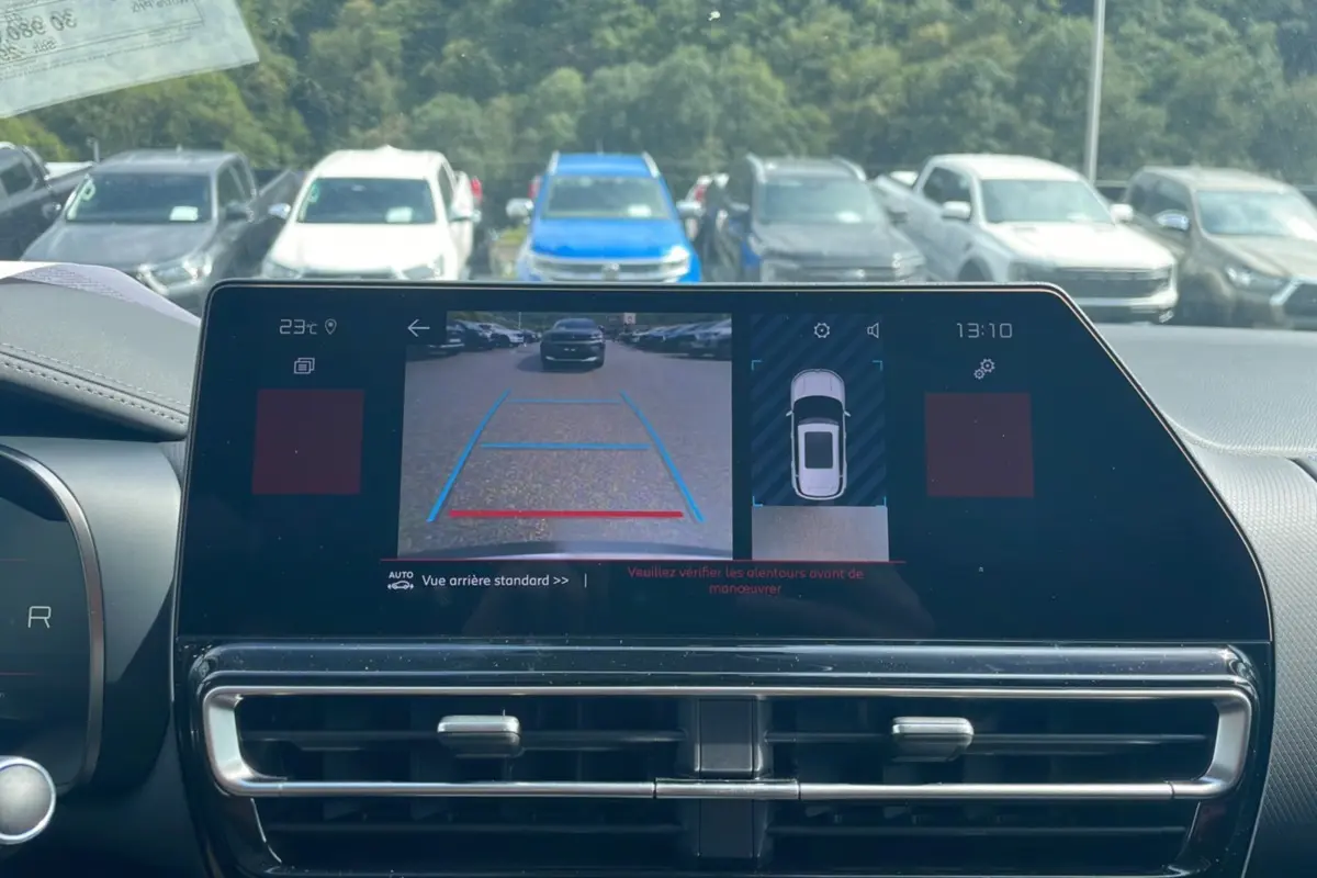 Vue arrière depuis la caméra de recul du Citroën C5 Aircross Hybrid blanc avec toit noir, affichée sur l'écran intérieur.