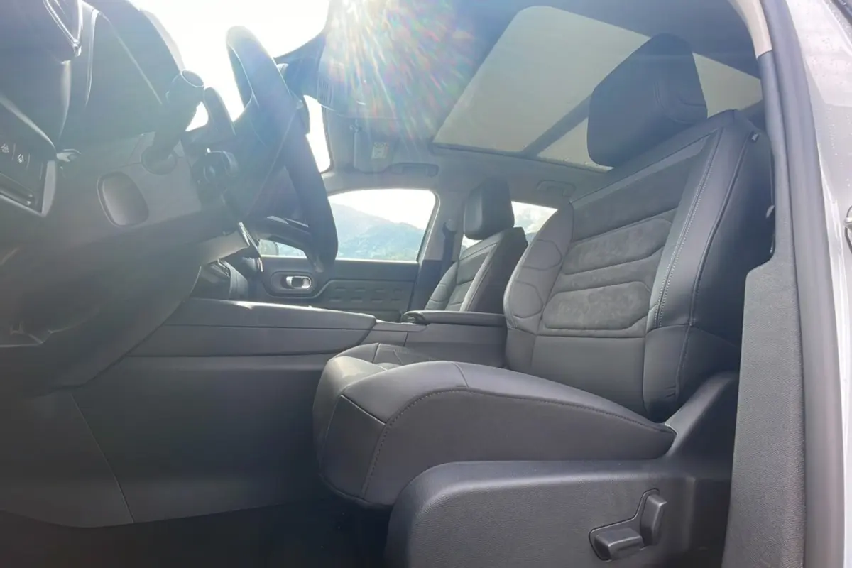 Intérieur du Citroën C5 Aircross Hybrid 2025 vu côté conducteur, sièges noirs et toit panoramique lumineux.