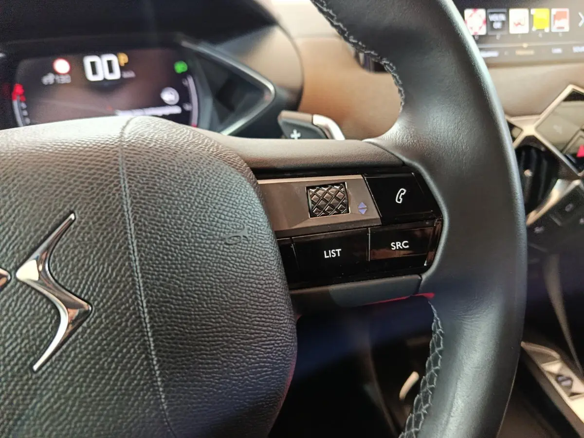 Gros plan sur le volant cuir noir du DS3 Crossback 2020 avec commandes vocales et écran numérique en arrière-plan.