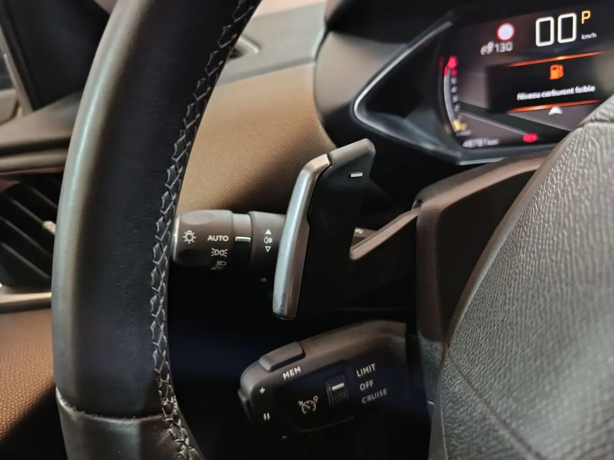 Gros plan sur le volant cuir et les commandes de régulateur de vitesse du DS3 Crossback gris foncé, tableau de bord numérique visible.