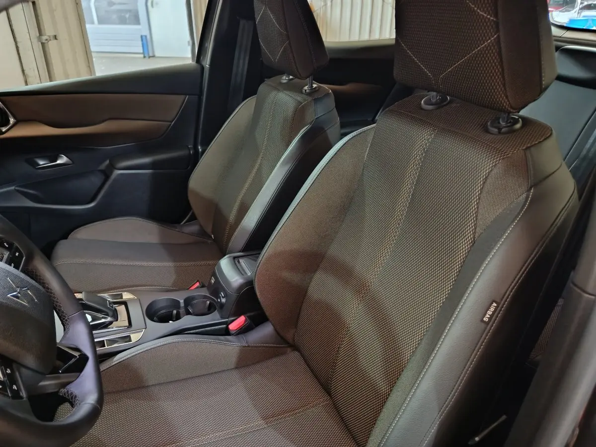 Vue intérieure côté gauche des sièges avant gris foncé du DS3 Crossback avec volant cuir et console centrale visible