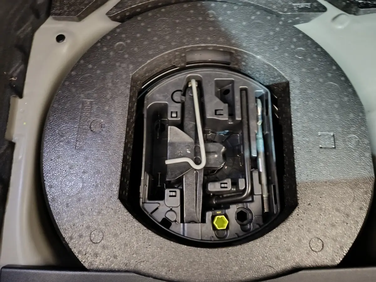 Gros plan sur la roue de secours galette et son kit d'outils dans le coffre du DS3 Crossback gris foncé.