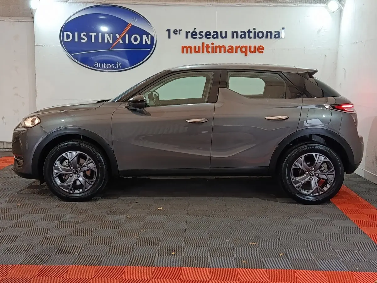 Vue latérale côté gauche d'un DS3 Crossback gris foncé garé en intérieur avec jantes alliage et feux arrière LED allumés.