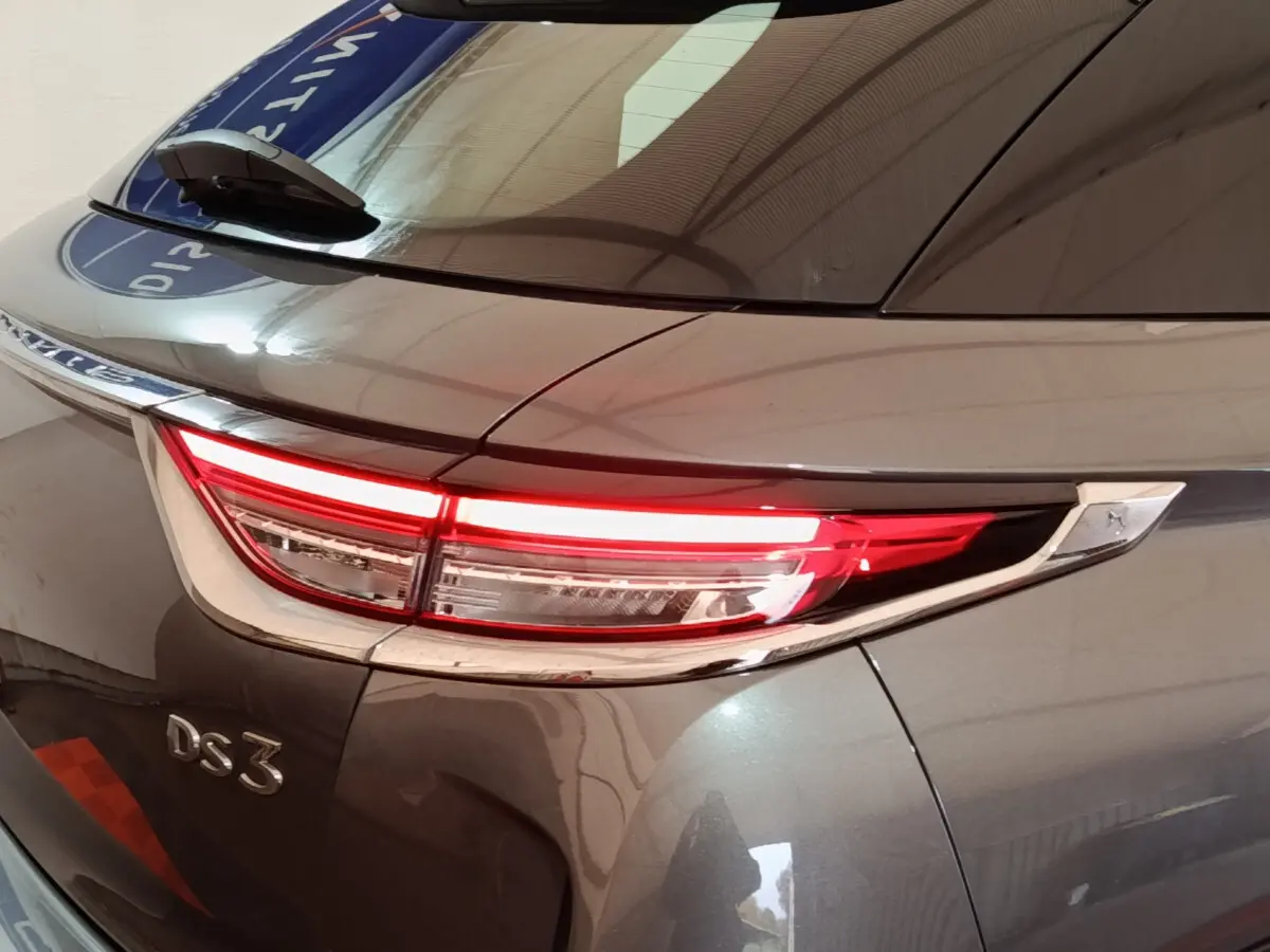 Gros plan sur le feu arrière droit allumé d'un DS3 Crossback gris foncé, soulignant la finition chromée autour du feu.