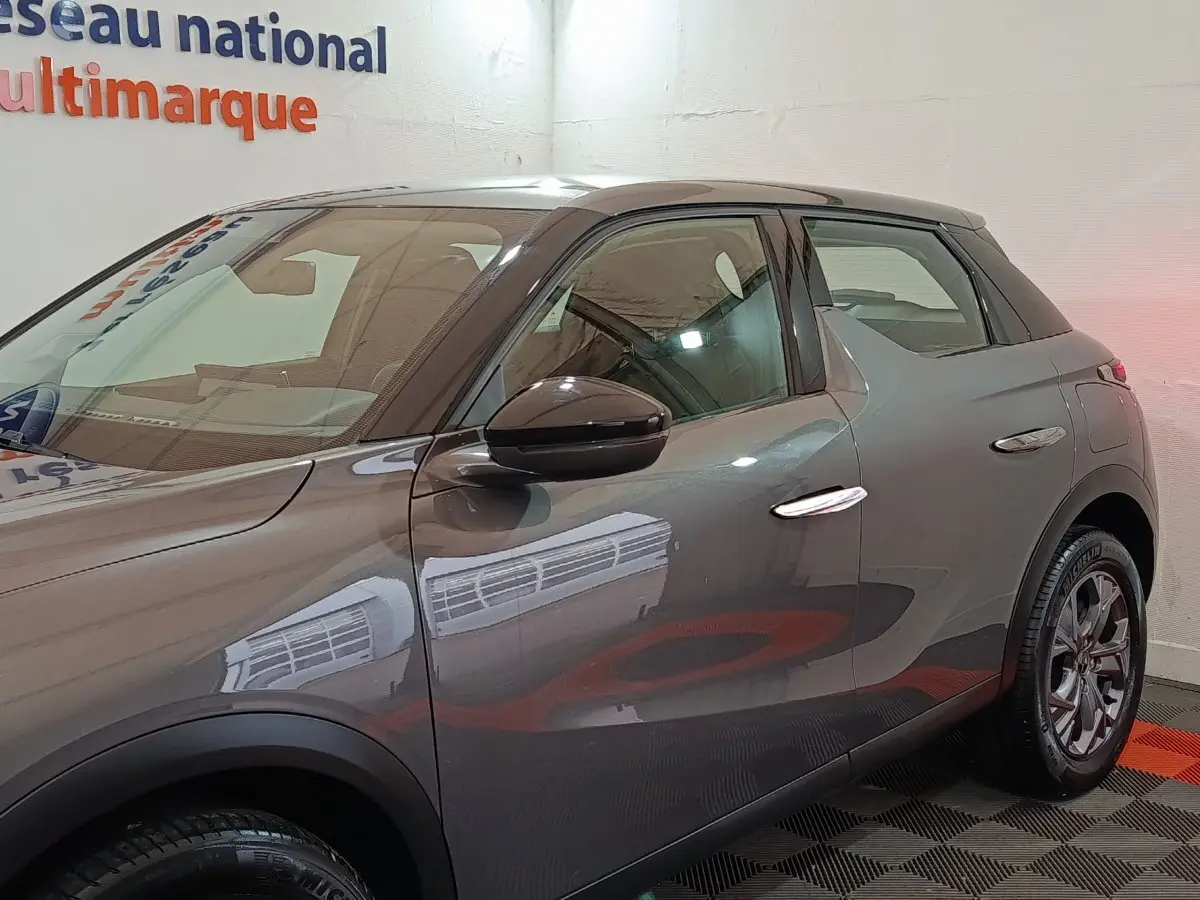 Vue côté gauche d'un DS3 Crossback gris foncé 2020 avec poignées chromées et jantes alliage.