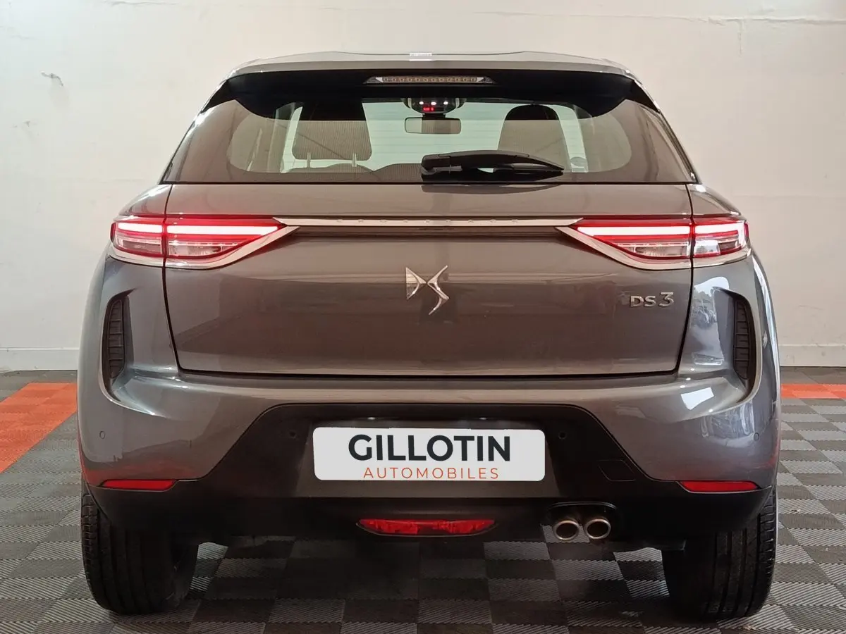Vue arrière d'un DS3 Crossback gris foncé avec feux LED étirés et double sortie d'échappement visible à droite.