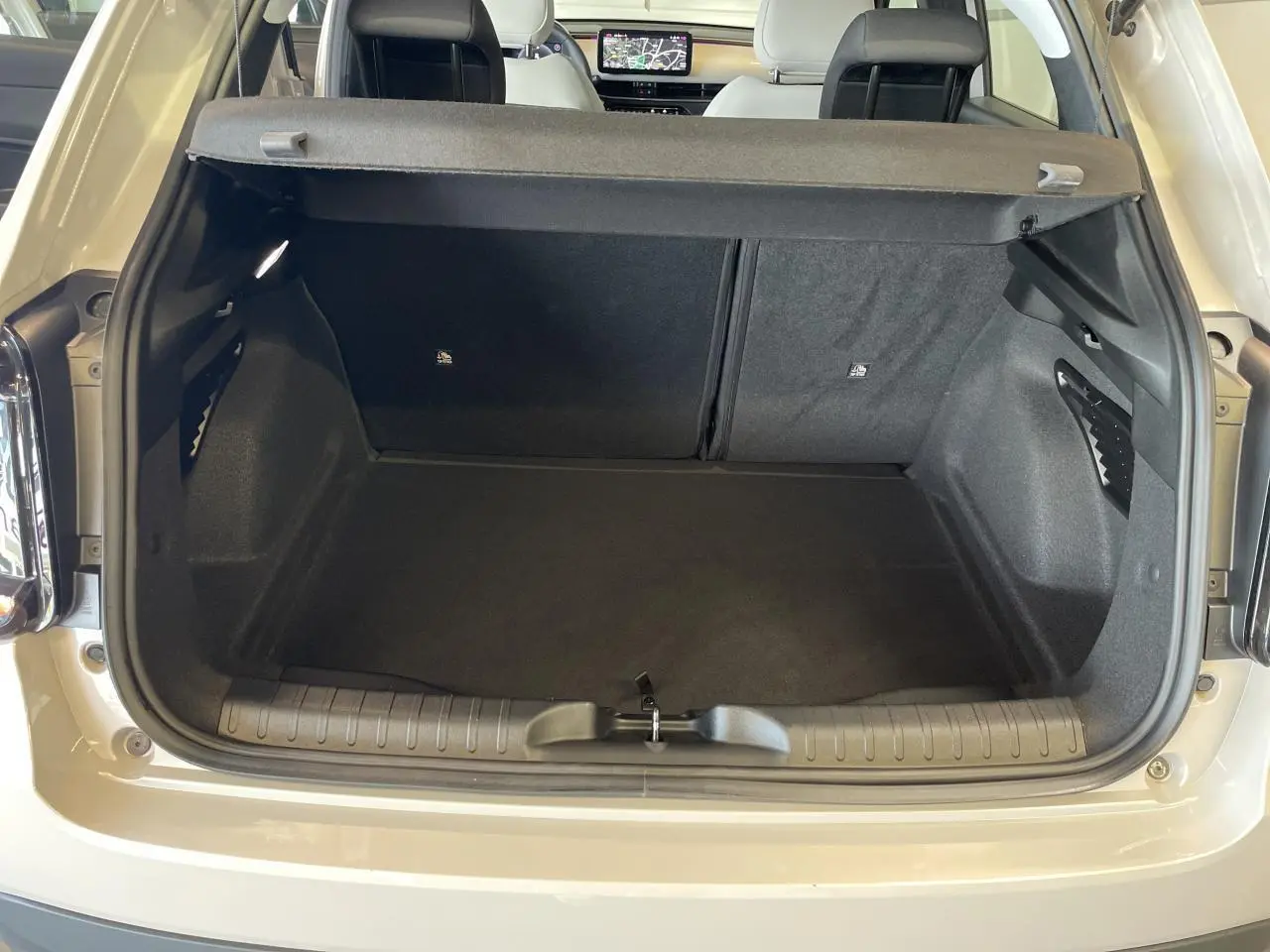 Coffre ouvert vu de l'arrière d'une FIAT 600 beige métallisé avec banquette arrière rabattable et planche de bord visible.