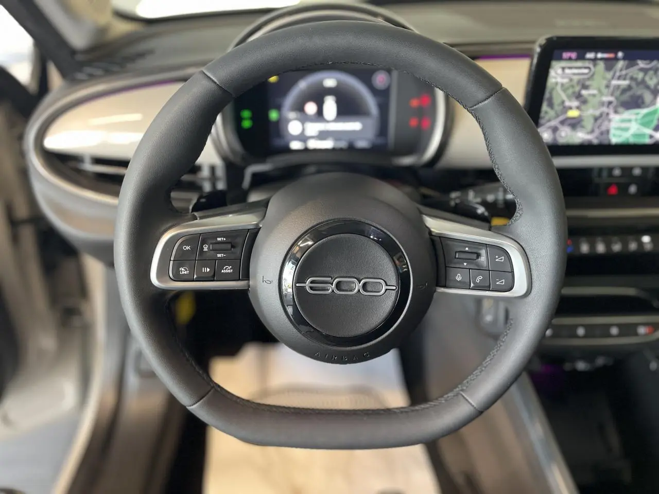 Volant noir du Fiat 600 1.2 Hybrid 2025 avec commandes intégrées et tableau de bord numérique en arrière-plan