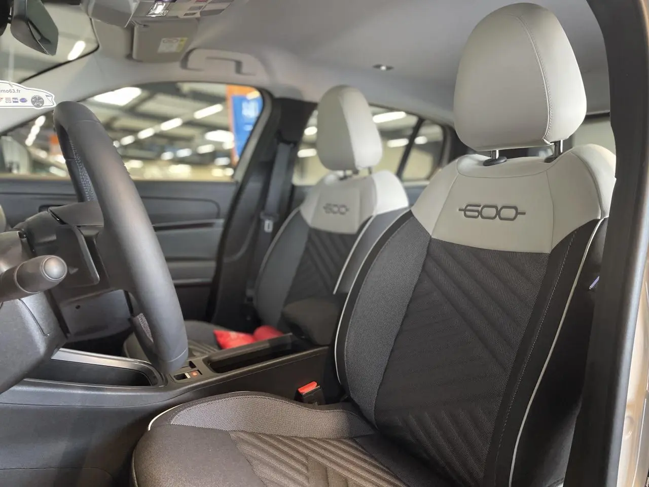 Intérieur du FIAT 600 beige métallisé, vue côté conducteur sur les sièges avant bicolores avec logo 600 brodé.
