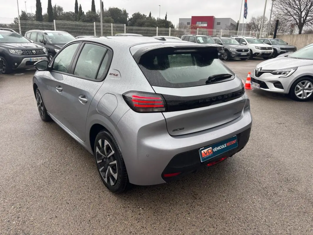 Vue 3/4 arrière droite d'une Peugeot 208 Hybrid gris 2025 avec jantes 16 pouces et logo Style sur l'aile arrière.